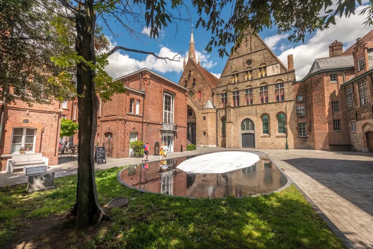 contemporary artwork The Veins of the Monastery at the Old St. John's site, a white marble island with black veins, surrounded by water with a dripping tree next to it.