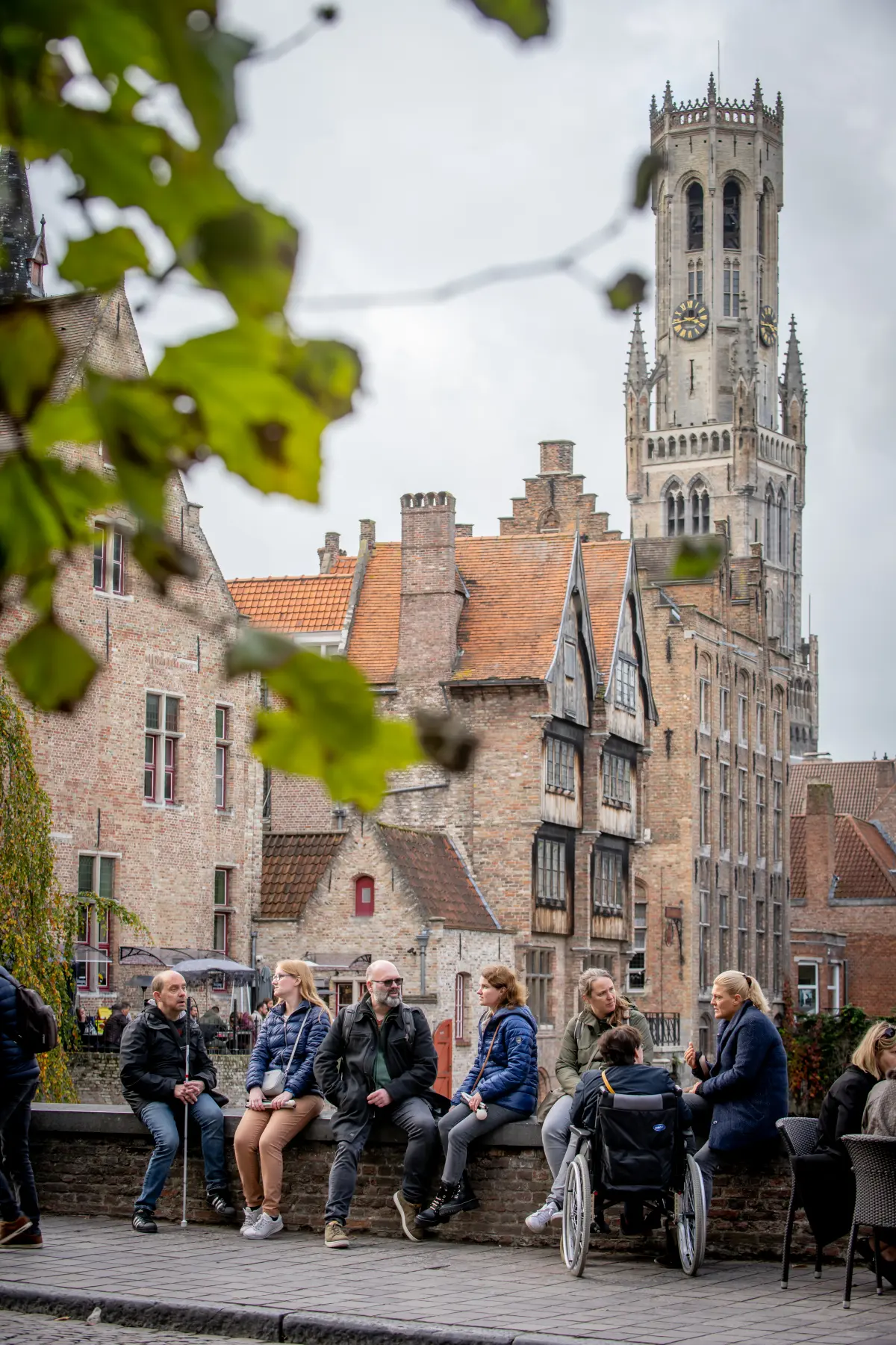 visitors on the Rosary Quay with historical facades and the Belfry in the background