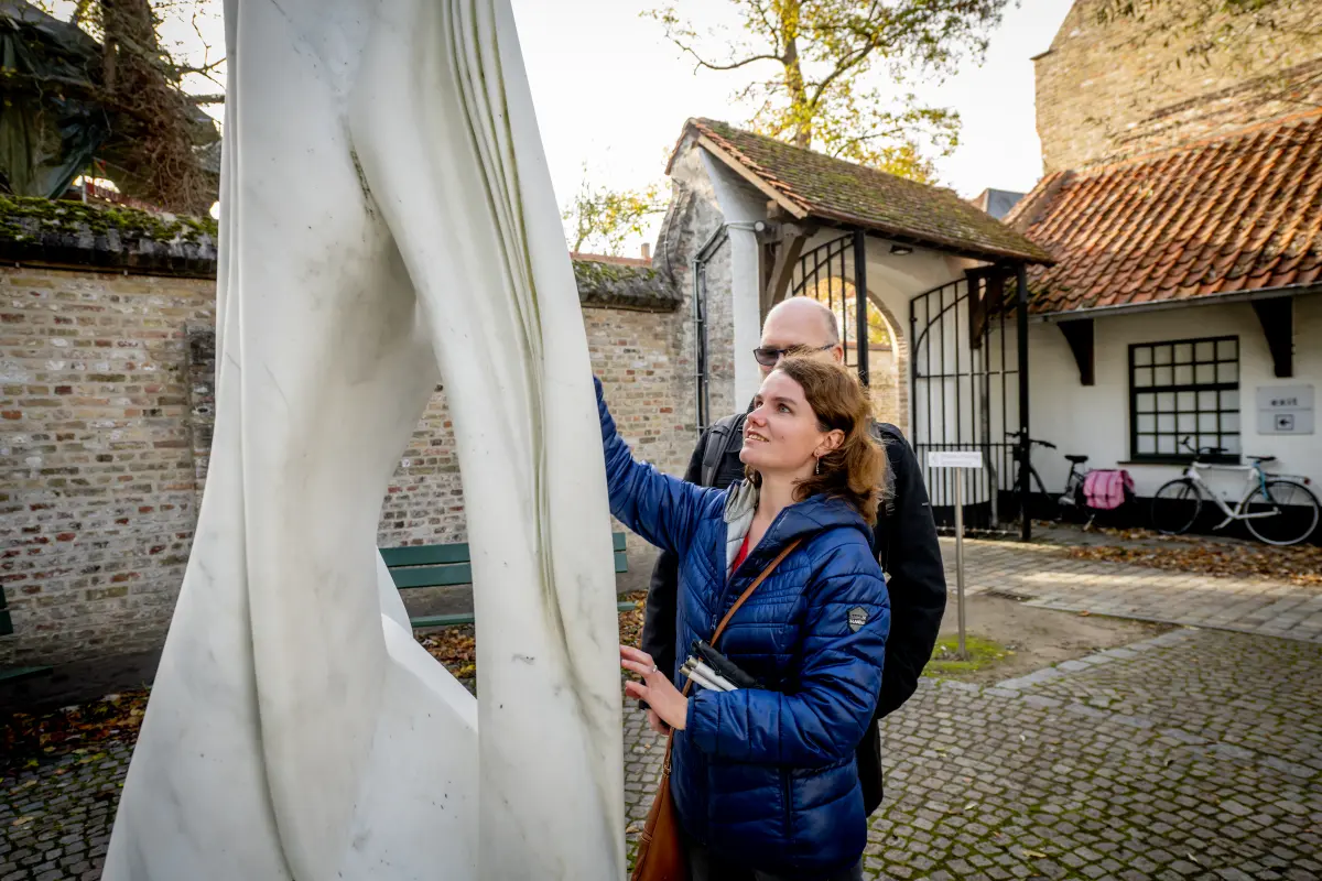 Blind woman feels the sculpture Untitled in the courtyard of the Groeninge Museum