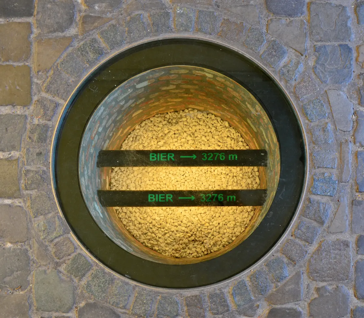 hole in the ground with a glass cover showing two pipes